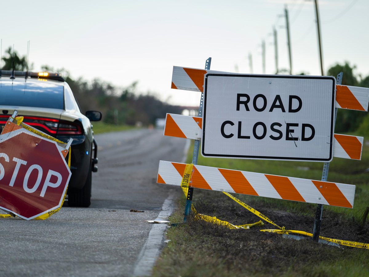 Patrol car with a stop paddle at a road-closed barricade